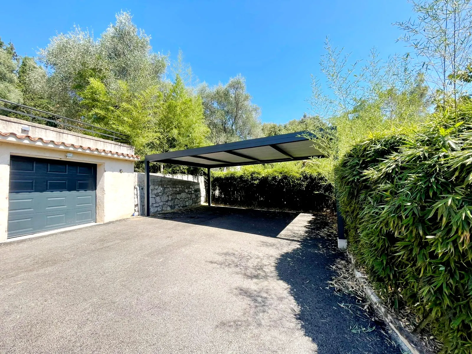 Carport aluminium intégré dans un environnement végétal arboré