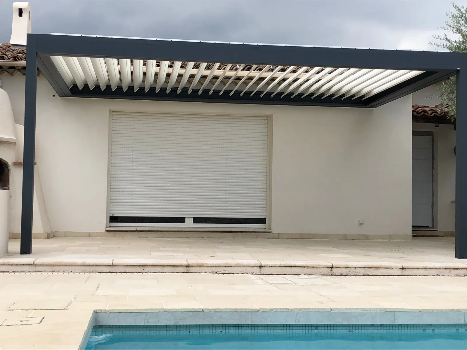 Pergola bioclimatique aluminium à lames orientables installée en bord de piscine