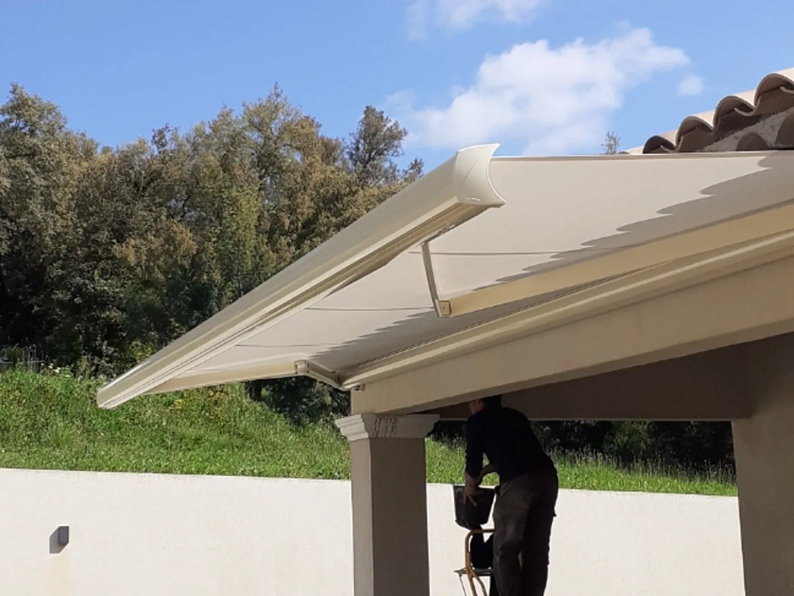 Poseur Art & Fermetures ajustant un store banne sur une terrasse